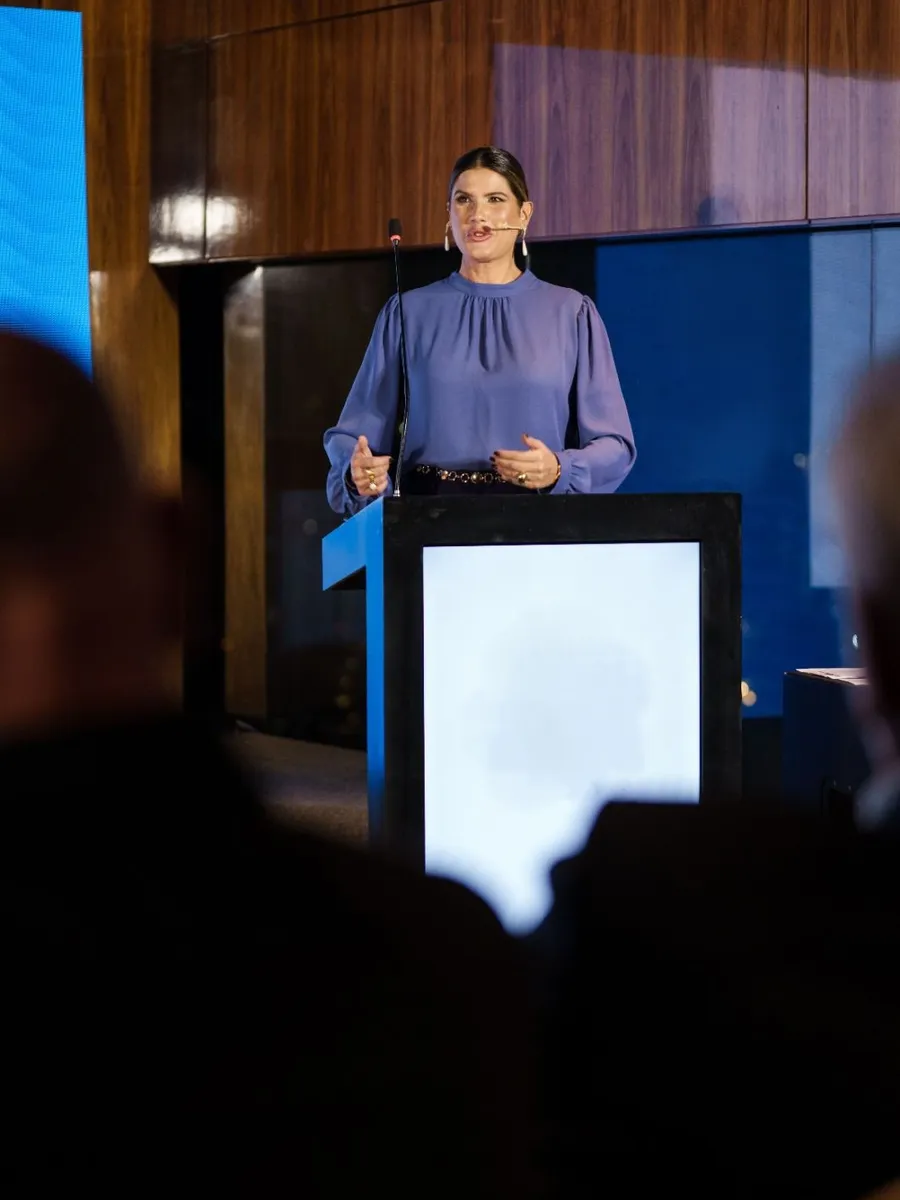Adriana Reid apresentando em palco, com microfone de lapela